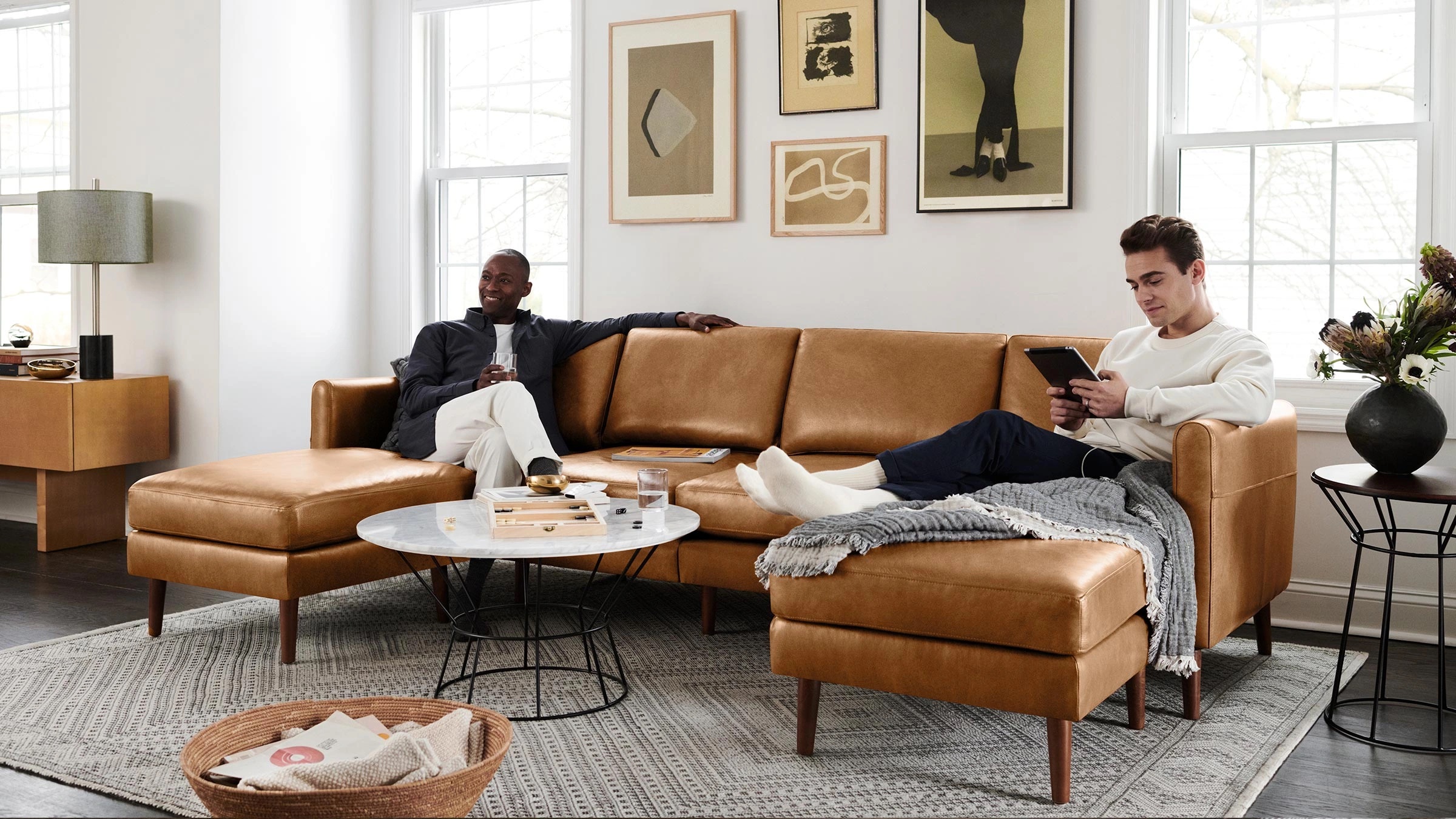 A couple lounges on a Burrow couch in a styled living room.